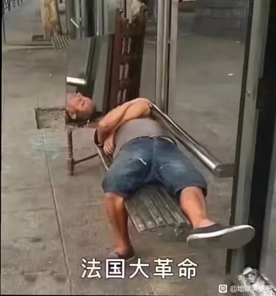 这是一张网络热梗图，素材为实拍的街景画面，图中一名穿着灰色背心、牛仔短裤的中老年男子非常放松地斜躺在街边的金属长椅上，整个人呈完全不想动弹的躺平状态，图片底部配文“法国大革命”，利用中文谐音对应“乏过大个命”的表述，意思是疲惫到仿佛半条命都没了，用来调侃当代人出门社交交朋友时精力消耗过大、只想躺着休息的状态。