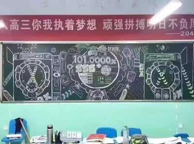 高三教室场景，黑板上方悬挂红色励志横幅，写有“高三你我执着梦想 顽强拼搏明日不负——204”。黑板主体为创意粉笔手绘，融合高考主题与游戏化元素，中央突出“高考 101.0000%”“SSS+”等字样，两侧对称绘制圆形仪表盘图案，周围点缀书本、闹钟、云朵等符号，整体呈现出将备考压力转化为趣味表达的青春气息。