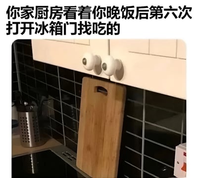 图片展示了一个厨房角落场景，白色橱柜下方挂着一块木质砧板，背景是黑色瓷砖墙面，台面上有金属厨具收纳筒。图片上方配有文字“你家厨房看着你晚饭后第六次打开冰箱门找吃的”，通过拟人化的手法幽默调侃了人们晚饭后频繁打开冰箱寻找零食的常见行为，内容贴近日常生活，充满轻松搞笑的氛围。