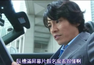 图片中一名穿着灰色西装的男子坐在汽车驾驶座上，侧身向左看，表情带着明显的困惑和惊讶。背景是城市高楼大厦，显示出繁华的都市环境。图片底部有紫色字幕：“卧槽满屏幕片假名鬼看得懂啊”，直白表达了对满屏片假名（日语文字）无法理解的吐槽情绪。