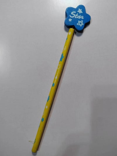 一张展示蓝色星星魔法棒玩具的图片。魔法棒顶部是蓝色五角星形状，上面用白色写着"Star"字样并装饰有小五角星图案。手柄是黄色的，上面印有蓝色小花和白色星星图案。整个玩具放置在浅色平面上，呈现出简洁可爱的儿童玩具风格。