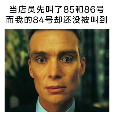 这是一张贴合日常场景的搞笑梗图，上方配有文案“当店员先叫了85和86号而我的84号却还没被叫到”，下方是电影《奥本海默》中主角的面部特写截图。图中人物双眼圆睁，眼神里满是震惊与不敢置信，面部肌肉紧绷，精准地还原了人们在排队叫号时，自己的号码被跳过、后面的号码先被叫到的那种错愕、无语又茫然的情绪，能够引发有过类似经历的网友的强烈共鸣，用电影中极具张力的表情来放大日常小事带来的情绪，显得诙谐又真实。
