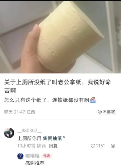 这张图是社交媒体发言截图，上半部分是一只手拿着一卷浅黄色的原生木浆卷纸，下半部分是用户的发言和评论区内容：发文用户（昵称嘤嘤嘤）吐槽自己上厕所没纸叫老公拿纸，抱怨命苦只有卷纸可用，没有更柔软的抽纸；下方有网友玩谐音梗评论“上厕所你用 集贸抽纸”，谐音中文粗俗脏话“几把抽纸”，而发文的用户没有听懂这个谐音梗，反而回复评论说“感谢推荐”，形成强烈反差笑点。