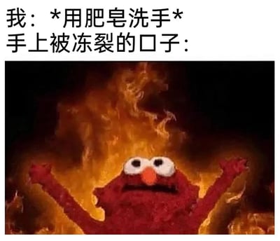 这是一张讲述冬天手冻裂体验的搞笑梗图，图片上方配有文字“我：*用肥皂洗手* 手上被冻裂的口子：”，下方是经典的“燃烧艾摩”画面：芝麻街的红色卡通角色艾摩被熊熊大火包围，高举着双手，创作者用这个画面夸张拟人地表现出冻裂的伤口碰到肥皂时那种强烈刺痛灼烧的感受，非常贴合很多人冬天手冻裂后的真实体验，容易引发共鸣。