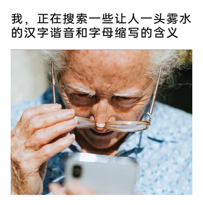这是一张图文混排的静态梗图，上方配有文字“我，正在搜索一些让人一头雾水的汉字谐音和字母缩写的含义”，下方是一位白发老年女性的真实照片：她满脸皱纹，将眼镜推到额头处，眉头紧皱，低头凑近手中的智能手机，眼神里满是困惑，手部的皮肤状态也凸显出她的年纪。整幅图通过老人的神态、动作搭配文字，生动展现了当下老年人面对网络中层出不穷的谐音梗、字母缩写等网络热词时的茫然与不解，精准戳中了网络文化存在代际差异的社会现象，容易引发不同年龄段用户的共鸣。