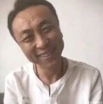 图中是一位短发男性，身穿白色上衣，面部表情夸张滑稽，眼睛微眯，嘴角上扬，背景为浅色墙面，整体给人一种搞笑、轻松的感觉。