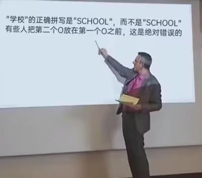 图片中一名穿着西装的男子正站在投影屏幕前，手持教鞭指向屏幕上的文字。屏幕内容显示：“学校的正确拼写是‘SCHOOL’，而不是‘SCHOOL’ 有些人把第二个O放在第一个O之前，这是绝对错误的”。画面的核心笑点在于所谓的“正确”与“错误”拼写完全一致，男子却一本正经地指出子虚乌有的“字母顺序错误”，形成强烈的荒谬感和幽默感。