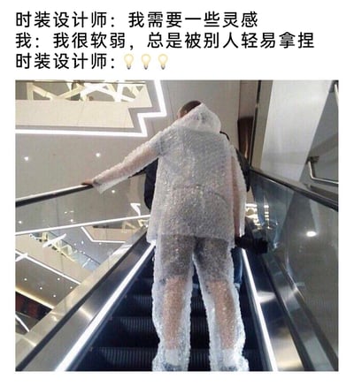 这是一张图文结合的搞笑网络梗图，上方的对话构建了一个趣味场景：时装设计师寻求灵感时，「我」吐槽自己性格软弱总是被他人「拿捏」，设计师随即灵光一闪。下方的图片展示了一套完全由气泡膜制作的连帽上衣加长裤的套装，穿着这套衣服的人正站在商场的自动扶梯上。该梗玩了「拿捏」的双关含义，既指精神层面上被他人牵制，也对应气泡膜可以被捏爆的物理特性，将日常吐槽转化为荒诞的时装设计灵感，用夸张的视觉效果制造出搞笑荒诞的氛围，调侃了软弱的自身状态。