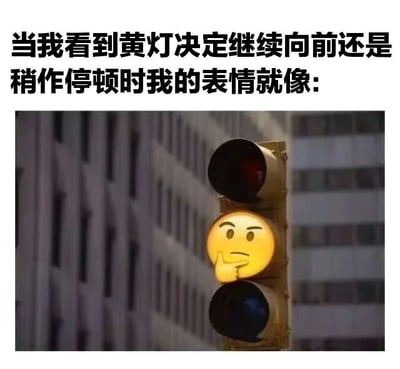 图片上方是黑色文字：'当我看到黄灯决定继续向前还是稍作停顿时我的表情就像:'，下方是一张交通信号灯的照片，其中黄灯部分被替换成了一个黄色的思考表情emoji（🤔），表情眉头微皱，食指抵着下巴，形象地表现出面对黄灯时犹豫纠结的心理状态。背景是模糊的城市建筑，突出交通灯主体。