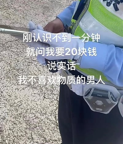 这是一张带有调侃文字的实拍静态图，画面展示了一名身着制服、戴白手套的交通警察手持开单设备的手部特写，背景是粗糙的路面。图片上的配文以类似男女交往吐槽的语气，将交警开具20元罚单的正常执法行为，调侃成“刚认识不到一分钟就问我要20块钱，说实话我不喜欢物质的男人”，通过反差感制造出搞笑的效果，用玩梗的方式消解了被开罚单的郁闷情绪。
