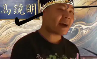 这是一张P图改编的真人趣味图像，图中真人被添加了带有长翅的古代官帽，人物嘴巴大张，表情夸张，头部抬起朝向斜上方，背景是带有海浪图案的古画风格画面，左上角标注有文字“高镜明”，整体风格搞笑恶搞，是对真人照片进行旧图再创作的内容，通过真人与古代元素的反差营造出趣味效果。