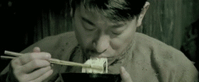 动图中一名男子身着朴素衣物，在昏暗的环境下低头用筷子艰难地挑起面条送入口中，随后用手捂住额头揉搓，神情充满悲伤与无奈。整个画面通过人物吃面的动作和痛苦的表情，生动诠释了“关灯吃面”这一网络流行语所蕴含的失意与沮丧情绪，原本特指股市投资失败后的绝望，现也广泛用于表达各种生活中的不顺与心碎时刻。