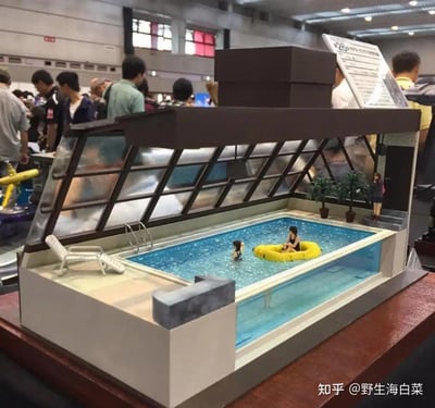 图片展示了在一个展览会上的精致泳池模型。模型内有蓝色的池水，两个微型人偶在水中，其中一个坐在黄色的充气圈上。模型上方有玻璃天窗，旁边配有白色的躺椅和小型盆栽。背景中有许多参观者在走动，显示出展览的热闹氛围。右下角有水印'知乎 @野生海白菜'。