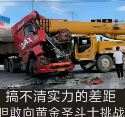 这是一张基于真实交通事故制作的梗图，画面中红色JMAX重型卡车的驾驶室严重损毁，正面撞上了黄色的徐工（XCMG）吊车，地面散落着大量车辆碎片，一名男子站在吊车旁查看情况。图下方配有调侃文字“搞不清实力的差距 胆敢向黄金圣斗士挑战”，用《圣斗士星矢》中的“黄金圣斗士”来比喻吊车的坚固属性，以幽默的方式调侃红色卡车错误估计了与吊车的强度“实力差距”，凸显两车在事故中的受损程度差异。