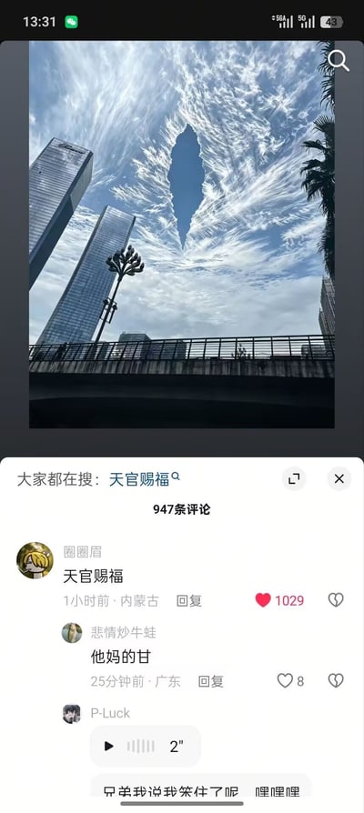 这张竖版截图分为上下两个部分，上半部分是仰拍的城市户外景观：画面左侧有两栋高层玻璃幕墙摩天大楼，中间有特色造型的路灯，下方是道路护栏，右侧有棕榈树叶的边缘，上方的天空布满丝絮状的白色云朵，云朵中间自然露出的狭长蓝色天空形状酷似菱形/水滴形，极具辨识度；下半部分是社交平台的评论区界面，顶部显示“大家都在搜：天官赐福”，共有947条评论，展示的三条评论分别为：用户“圈圈眉”发布的“天官赐福”，获1029个点赞，发布地为内蒙古；用户“悲情炒牛蛙”发布的“他妈的甘”，获8个点赞，发布地为广东；用户“P-Luck”发布的一条2秒语音，语音转文字内容为“兄弟我说我呆住了呢 嘿嘿嘿”。