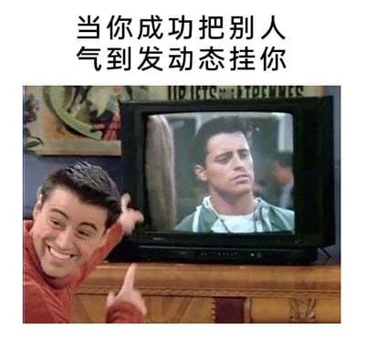 这是一张基于美剧《老友记》制作的搞笑梗图，顶部配文为“当你成功把别人气到发动态挂你”。图中通过拼接演员马特·勒布朗饰演的乔伊的两种状态：画面左侧的乔伊咧嘴大笑，兴奋地用手指向电视，满脸得意；电视屏幕里的乔伊则面色不悦、神情烦躁。用同一个人物的强烈反差状态，生动调侃了生活中那种把别人惹生气，看到对方公开发动态吐槽自己时，不仅不心虚反而充满成就感、觉得自己“赢了”的欠欠的搞怪心态，十分贴合日常里的搞笑社交场景。