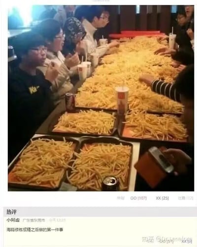这张图呈现了一群人围坐在长桌旁的场景，整个桌面被数量惊人的薯条完全铺满，几乎看不到桌面，旁边搭配着可乐和连锁快餐店的饮料杯，人们正专注地享用这些薯条。图片下方是社交媒体的评论区域，热评内容为“海鸥修炼成精之后做的第一件事”，这个评论是玩梗：海鸥以喜爱抢食薯条著称，这个堆满薯条的场景如同成精的海鸥实现了“薯条自由”，用夸张的调侃放大了场景的趣味性。