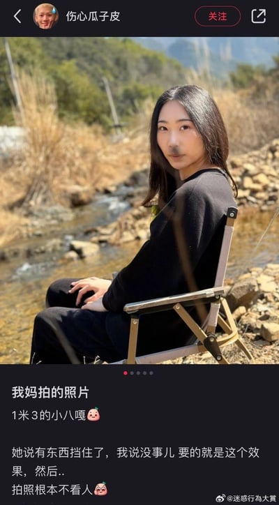 社交媒体截图中，一位女子坐在溪边折叠椅上，背后是山林与溪流，前景有植物茎秆部分遮挡面部。配文吐槽妈妈拍照技术：“我妈拍的照片 1米3的小八嘎😋 她说有东西挡住了，我说没事儿要的就是这个效果，然后.. 拍照根本不看人🤦‍♀️”，幽默展现长辈拍照只看风景不看人的搞笑场景，充满生活气息与无奈又好笑的家庭互动。