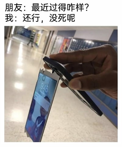 这是一张图文结合的自嘲类网络梗图，上方是一段日常对话：朋友关切地询问“最近过得咋样？”，“我”则用“还行，没死呢”这种带着消极戏谑感的语气回应；下方是一只手握着一部完全破碎的手机，手机的屏幕与机身彻底分离成两半，但屏幕依然亮着，显示着时间9:45和一张人物照片。这张图用破碎到极致的手机来比喻自己糟糕、支离破碎的生活状态，通过夸张的视觉元素和自嘲的文字，精准表达出当代年轻人在面对生活压力时，过得不如意却又不得不硬撑的心态，是一种用搞笑方式宣泄负面情绪的内容。