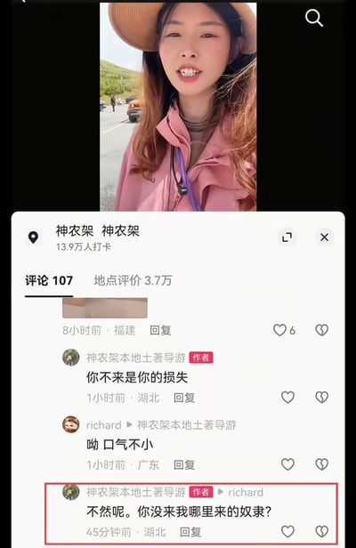 图片展示了一个社交媒体平台上的旅游地点页面，上方是一位戴着帽子、穿着粉色外套的女性在神农架景区的照片，下方是评论区的争议对话。一位名为'神农架本地土著导游'的用户在回复中发表不当言论：'不然呢。你不来我哪里来的奴隶？'，该评论被红色方框重点标注。此截图因导游使用'奴隶'一词引发争议，反映了旅游服务中的不当言论问题。