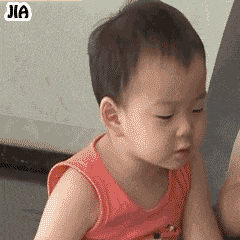 这是一张动态GIF表情包，内容为一名穿着橙色上衣的小孩，面部表情随帧变化，从低头到皱眉再到张嘴，配合重复出现的橙色黑边文字“蠢不蠢啊”，整体呈现出一种嫌弃、调侃的语气，常用于对他人行为表示无奈或开玩笑式的吐槽。
