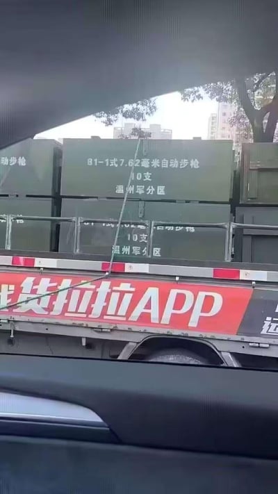 透过汽车车窗拍摄到一辆货拉拉货运车，车厢内装载着多个军绿色箱子，箱子上清晰标注着「81-1式7.62毫米自动步枪 10支 温州军分区」的字样，货车侧面带有醒目的红色「货拉拉APP」车身广告。图片的核心看点在于民用货运平台运输军用枪械物资的强烈反差感，容易引发网友的好奇与讨论。