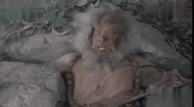 这是一段出自1995年TVB版《神雕侠侣》的动态GIF截图，画面中饰演周伯通的黎耀祥头发花白凌乱，身着破旧的古装，躺在石堆与植被旁，肢体做出动作，表情激动亢奋，完美还原了周伯通天真跳脱、不受拘束的经典形象，常被用作表情包来表达激动、耍赖、随性的情绪。