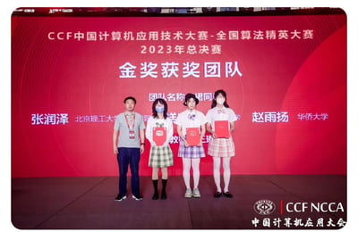 图片展示了CCF中国计算机应用技术大赛-全国算法精英大赛2023年总决赛的金奖获奖团队领奖现场。背景为红色主题的大型屏幕，上面清晰显示赛事名称、年份及“金奖获奖团队”字样。舞台上共有四人，从左至右分别为北京理工大学的张润泽、两名身着校服风格服装的团队女成员、华侨大学的赵雨扬，四人手中均持有红色获奖证书，姿态正式站立。屏幕上还标注了团队名称（部分文字模糊）及成员所属院校信息。整体场景庄重且充满荣誉感，展现了获奖团队的风采。
