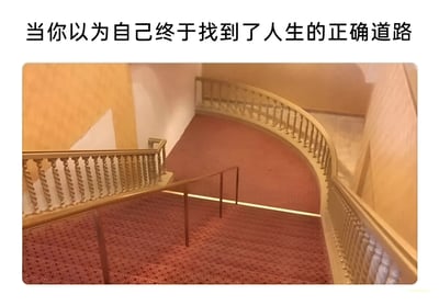图片上方配有文字'当你以为自己终于找到了人生的正确道路'，下方是一张螺旋楼梯的照片。楼梯铺着红色地毯，两侧有金色雕花栏杆，整体呈现出蜿蜒曲折、似乎没有尽头的结构。图片通过楼梯的视觉隐喻，表达了人们以为找到正确人生方向，却可能陷入循环或迷茫的无奈感受。