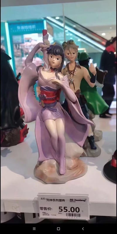 商场展示柜中陈列的原神系列角色手办。前景是一位身着紫色渐变和服式服装的女性角色手办，她手持长剑，姿态优雅，腰间系有红色腰带。其身后站立着一位穿着棕色上衣的男性角色手办。手办下方的价格标签显示零售价为55元。背景中可以看到商场环境，有自动扶梯和其他顾客。