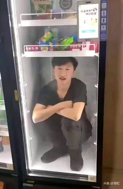 这是一张利用视觉错位制作的搞笑图片，将网络主播药水哥的照片贴在便利店的冷藏展示柜玻璃外侧，从正面视角看去，仿佛药水哥双臂交叉蹲坐在冷藏柜内部，营造出荒诞滑稽的搞笑效果，图中没有双关、谐音梗等内容。