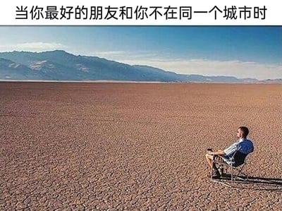 这是一张引发情感共鸣的网络梗图，图片上方配有文字“当你最好的朋友和你不在同一个城市时”，画面呈现出一片广阔无垠、土地干裂的荒漠，远处是连绵的山脉，整个场景空旷又孤寂；右下角有一名穿着格子衬衫的男子，坐在折叠椅上，独自望向远方，人物的渺小和环境的空旷形成强烈反差，精准地传达出好友分隔异地后，内心那种孤单、空落、无人陪伴的心境，很容易让有类似经历的人感同身受。
