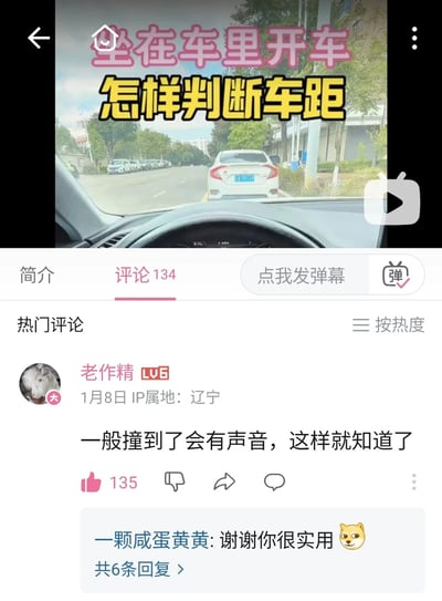 图片为社交媒体视频截图，上方显示视频标题'坐在车里开车 怎样判断车距'（粉色和黄色字体），背景是从车内驾驶位拍摄的前方道路场景，可见一辆白色轿车停在前方。下方为评论区界面，显示'评论134'及热门评论，其中用户'老作精'的评论'一般撞到了会有声音，这样就知道了'获135赞，下方有回复'一颗咸蛋黄黄: 谢谢你很实用'并配狗头表情包，整体内容结合驾驶教学主题与幽默互动评论。