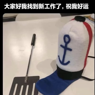 这是一张搞笑梗图，采用顶配底文的图文混排形式，顶部配文为“大家好我找到新工作了，祝我好运”，下方画面中在浅色桌面上摆放着两个物品：一个是动画《海绵宝宝》里蟹堡王员工佩戴的、印有蓝色船锚图案的同款毛绒帽子，旁边还有一把煎制食物用的长柄煎铲，玩的是“新工作是去蟹堡王当厨师做蟹黄堡”的梗，用夸张的方式调侃自己的新工作，充满搞笑自嘲的趣味。