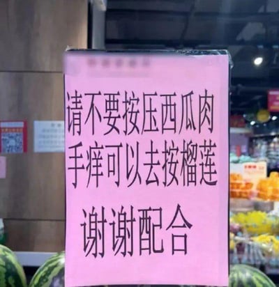这是一张在水果店拍摄的实拍照片，画面主体是一块粉色的提示牌，上面用黑色字体清晰写着“请不要按压西瓜肉 手痒可以去按榴莲 谢谢配合”。提示牌下方能看到摆放的西瓜，背景是水果店的货架和其他水果。该提示语用幽默风趣的方式劝阻顾客不要按压西瓜，利用榴莲外壳坚硬、按压也不会造成损坏的特点，既达到了提醒顾客避免损坏水果的目的，又因独特的表述方式让人觉得诙谐有趣，没有双关、谐音梗或暗示内容。
