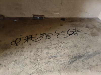 这是一张拍摄于老旧物件（或墙面）的照片，表面被大量随手涂写的文字覆盖。最醒目的是左侧爱心符号搭配艺术字体的“我爱你”，下方清晰写有唐诗《黄鹤楼送孟浩然之广陵》的完整内容，除此之外还有大量杂乱模糊、难以辨认的手写文字和英文，整体画面显得凌乱，呈现出被多人随意涂写的状态。