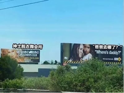户外场景下的两块并列广告牌，左侧为“绅士脱衣舞会所”(SEAMAN'S RHINO GENTLEMEN'S CLUB)广告，右侧为印有女性与儿童形象的广告牌，配文“爸爸去哪了？”(Where's daddy?)。两块广告牌内容形成鲜明对比，左侧的成人娱乐场所广告与右侧暗示父亲缺席的家庭主题广告意外同框，产生讽刺幽默的视觉效果。