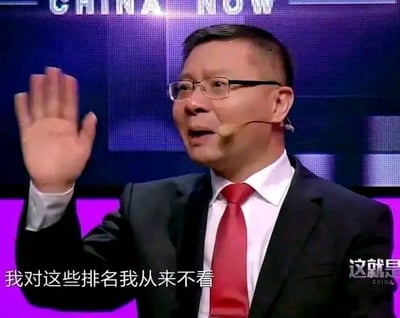 图片中一位戴着眼镜、穿着黑色西装和红色领带的男子正在挥手，他佩戴着耳麦，背景是带有"CHINA NOW"字样的蓝色屏幕。图片底部有文字"我对这些排名我从来不看"，右下角有"这就是"的标识。男子表情自信，动作自然，看起来像是在电视节目或公开演讲中表达对排名的不在意态度。