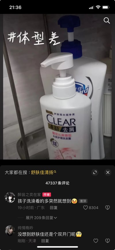图片主体为浴室场景中两瓶洗护用品的对比：前景是矮胖的清扬去屑洗发水瓶（白色瓶身，按压泵），背景是瘦高的舒肤佳沐浴露瓶（白色瓶身，蓝色按压盖），上方叠加文字“#体型差”，用网络流行语调侃两者高矮胖瘦的视觉反差。下方是社交媒体评论区截图，显示作者“醉翁之恋在家”留言“孩子洗澡看的多突然就想到”（获8304赞），及用户“纯情晚吟”评论“没想到舒肤佳还是个双开门呢”，整体营造出生活化的幽默氛围。