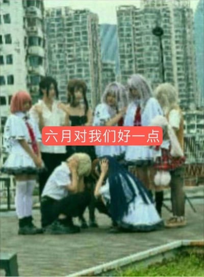 图片拍摄于户外，背景为高楼大厦，画面中有一群身穿二次元或日系cosplay服装的人物，有两人抱头蹲地，周围其他人围观或站立。画面正中添加了一句“六月对我们好一点”的大字，被广泛应用于网络表达吐槽、祈愿、压力大等情感。画面整体带有年轻、二次元文化和幽默自嘲气息。

此图没有明显双关和谐音梗，但“抱头蹲防”动作传达了一种压力大、无助或无奈的趣味，结合文案形成“六月生活太难了”的自嘲意味，常用于考试季、升学季、期末等时间段。