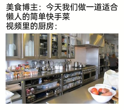 这是一张带有反差幽默的图文梗图，上方文字为美食博主宣称要制作适合懒人的简单快手菜，下方配图却是一个配置专业、空间宽敞的大型商用厨房，厨房内的超长不锈钢操作台上摆满了罐头食材、专业料理机、各类锅具，操作台下方和橱柜中也收纳着大量储物盒与厨具，还有多组专业炉灶，和“懒人快手菜”所需的简易厨房形成巨大反差，图中远处还有一人在厨房内活动，前景台面上摆放着装有蔬果的碗，整体通过这种强烈的反差感制造出吐槽美食博主“懒人菜”不接地气的幽默效果。