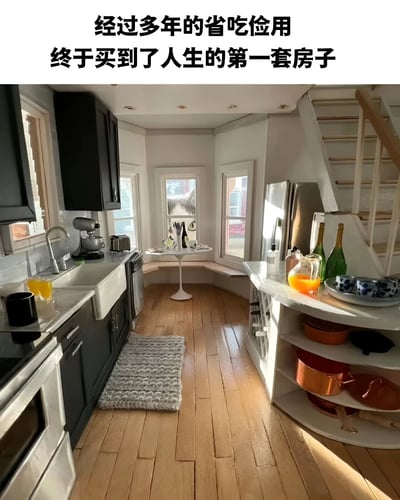 图片上方配有文字'经过多年的省吃俭用 终于买到了人生的第一套房子'，下方则是一个极其狭小的厨房空间，形成强烈反差。厨房内有黑色橱柜、不锈钢电器、木质地板和一个小餐桌，整体装修现代但空间非常局促。这种幽默表现了年轻人买房压力大，可能只能负担极小空间的现实。