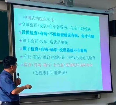 这是一张实拍的讲课现场照片，画面左侧有一名戴眼镜的男性讲师手持麦克风，正对着右侧的投影幕布进行讲解，幕布上的PPT以公式化的形式，总结了不同就医场景下部分患者对医护人员的刻板负面质疑逻辑，调侃了当前国内医患关系中存在的信任矛盾，还标注了未治愈的情况可能引发恶性事件，内容直白且具有现实讽刺性。