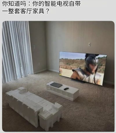 这是一张搞笑图文梗图，顶部配有文字“你知道吗：你的智能电视自带一整套客厅家具？”，下方实景图展示了刚拆封的智能电视靠在墙边正在播放影视内容，电视的白色泡沫包装盒被巧妙拼成了沙发和茶几的样式，泡沫茶几上还摆放了笔记本和遥控器，看起来就像是真的拥有了一整套完整的客厅家具，用调侃的方式展现了新电视拆封后、或是刚搬家时暂时用包装泡沫应急充当家具的有趣生活场景。