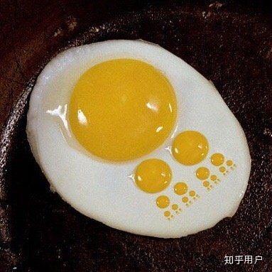 图片中展示了一个煎制金黄的荷包蛋，躺在深色的平底锅上。完整的蛋黄位于中央，呈现出诱人的光泽；而在蛋白部分，分布着几处小巧的黄色圆点，巧妙排列成一串微型脚印的形状，仿佛有一只看不见的小生物刚刚从柔软的蛋白上走过，留下了可爱的足迹。整体画面充满生活气息与创意巧思，给人一种轻松有趣的感觉。