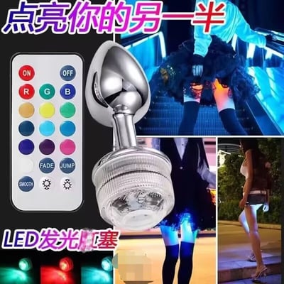 这是一张产品宣传图，主要展示LED发光肛塞及其使用效果。图片包含多个部分：左上角是带有ON/OFF按钮和多种颜色选择按钮的遥控器；中间是银色的LED发光肛塞产品特写；右上角和下方是多张女性使用该产品后，从身体下方透出彩色光芒的场景图，展示了不同颜色的发光效果。图片上方有“点亮你的另一半”的紫色大字标题，下方有“LED发光肛塞”的产品名称。