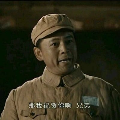 这是一张国产经典军旅电视剧《亮剑》的剧照截图，画面中的人物是赵刚，他身着解放战争时期的土黄色解放军军装，戴着同款军帽，面带笑容，神情真诚，似乎正在和对话对象交流。画面下方配有白色字幕，内容为“那我祝贺你啊 兄弟”，传递出一种真诚的祝贺语气，契合赵刚在剧中温和、正直且重情义的人物性格。