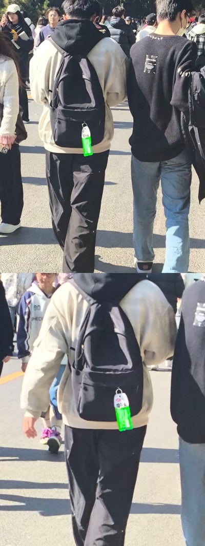 两张上下拼接的照片，均展示了一位行人的背影。此人穿着浅色连帽卫衣和黑色裤子，背着黑色双肩包，背包上挂着一个醒目的绿色小物品，疑似饮料瓶或挂饰。周围有许多行人，显示这是在一个拥挤的公共场所，可能是街道或活动场地。两张照片角度略有不同，下方照片更近距离展示了背包上的绿色物品细节。