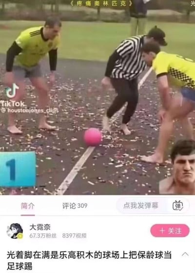 这是一张竖屏手机社交媒体视频截图。上半部分是户外场地中的“疼痛奥林匹克”挑战：两名穿荧光黄球衣的男子和一名穿黑白条纹服的裁判均赤脚站在铺满乐高积木的地面上，三人弯腰围向中线附近的一颗粉色保龄球，准备把保龄球当作足球踢。乐高积木硌脚本身已经非常疼痛，保龄球又坚硬沉重，使踢球动作更具痛感和荒诞感。画面顶部有《疼痛奥林匹克》标题，左下角有蓝色序号“1”，右下角叠加了一个表情严肃痛苦的男性特写。下半部分是B站移动端界面，显示UP主“大霓奈”、67.3万粉丝、8397条视频、309条评论，简介为“光着脚在满是乐高积木的球场上把保龄球当足球踢”。外部配文“很快他们会发现肘击别人比踢球更容易”以夸张方式调侃：在这种极端疼痛的规则下，球员可能觉得用肘部犯规都比正脚踢球更轻松，形成对足球比赛中犯规行为的戏谑影射。