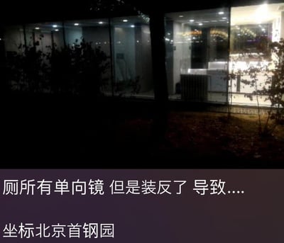 这是一张夜晚实拍的北京首钢园场景图，画面中建筑的玻璃墙面在室内亮灯的状态下，可清晰看到内部的厕所区域。图下配文指出该厕所的单向镜被装反了：正常单向镜的设计是室内人员可观察室外，室外无法窥视室内，而装反后则完全相反，室外人员能毫无遮挡地看清厕所内部情况，室内使用者的隐私会被暴露，极易引发社死或隐私泄露问题。